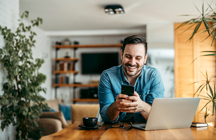 Vīrietis savās mājās skatās savā viedtālrunī